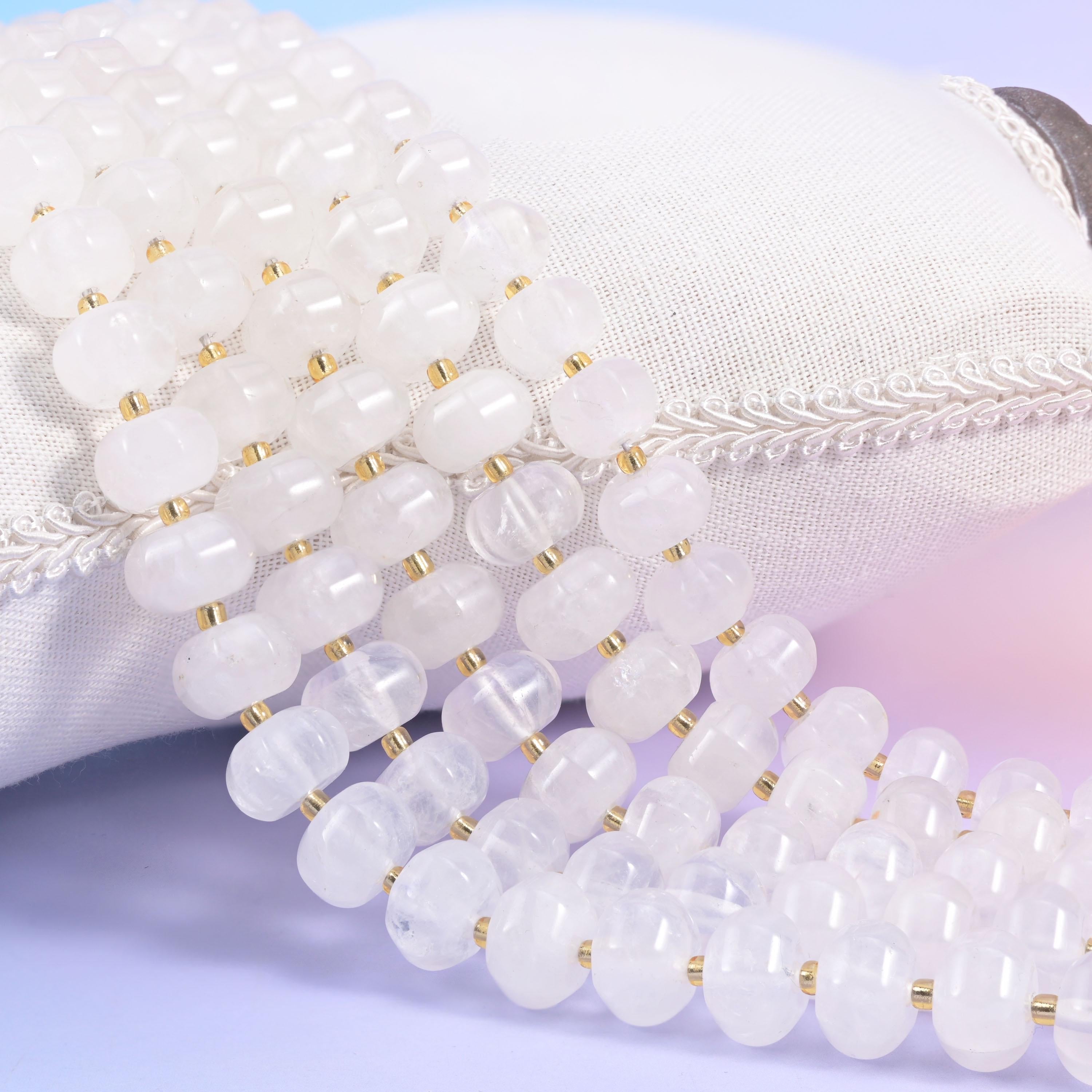 Clear quartz pumpkin rondelle strands on a white cushion, frosted white beads split by gold seed spacers
