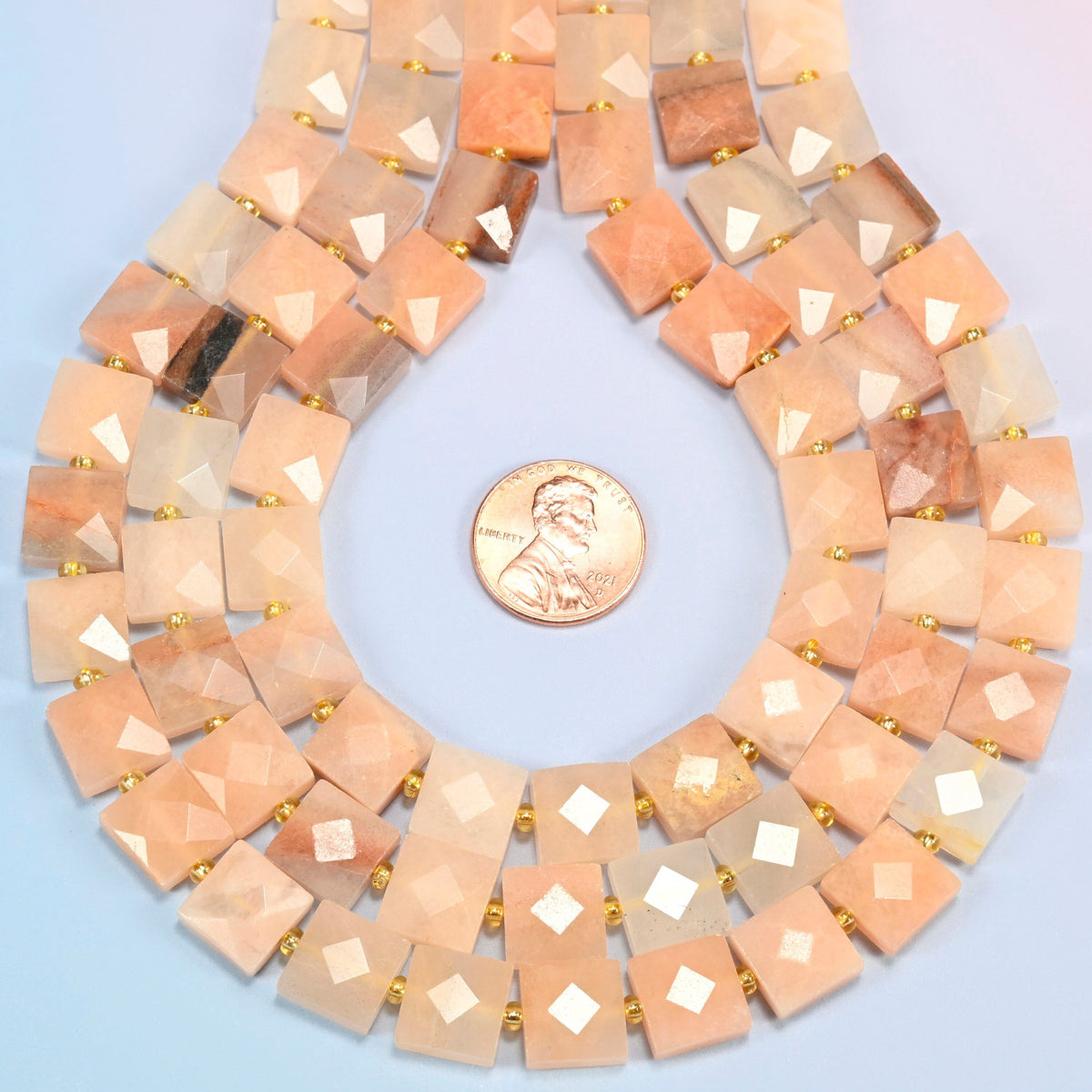 Natural pink aventurine faceted flat square strands formed into a teardrop loop around a US penny for scale