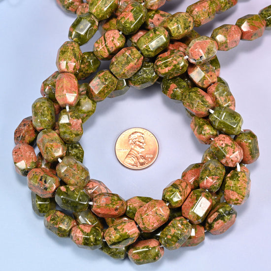 Wide circular coil of faceted Unakite barrel beads on a light blue background, showing the full wreath pattern.