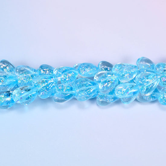 Iridescent light blue heart glass beads in a close straight row, showing the even moulded heart shape