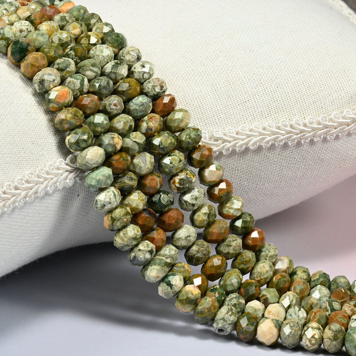 Snake skin jasper faceted rondelle beads 5x8mm in mottled sage green and rust brown, several strands draped over a white cushion