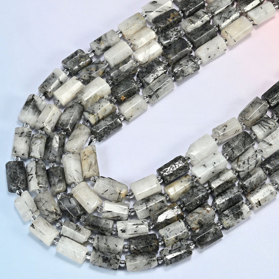 Black rutilated quartz faceted tube beads in several strands curved into a wide U, white quartz with black needles