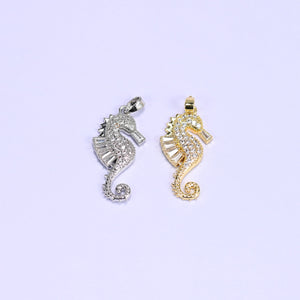 Sea horse zirconia charms in silver and gold, both pendants paved with round and baguette clear stones and finished with open bails.