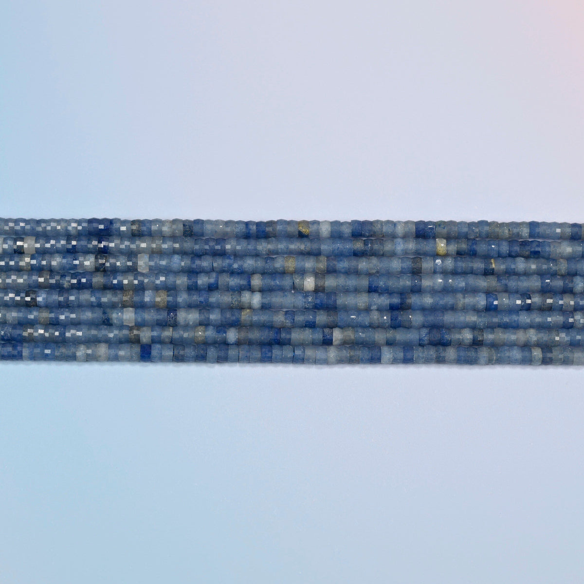 Several strands of blue aventurine faceted heishi disc beads laid in straight rows
