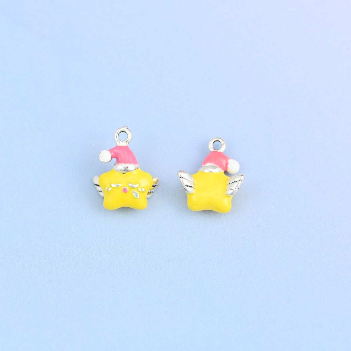 Two star charms in pink hats, one turned to show the plain back and the raised silver-tone wings.