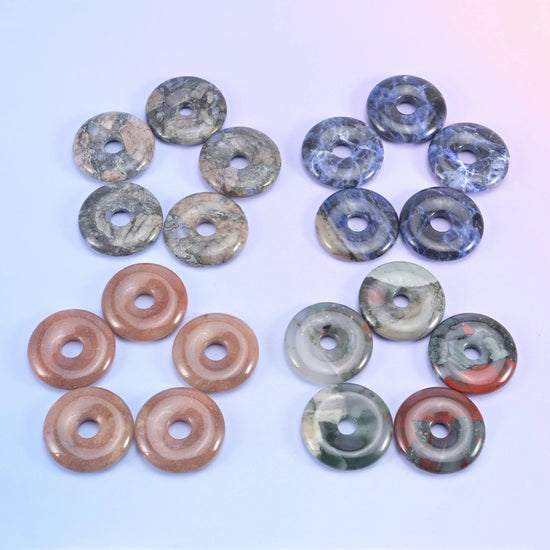 Four sets of donuts, blue spot jasper and sodalite beside warm brown and grey stones