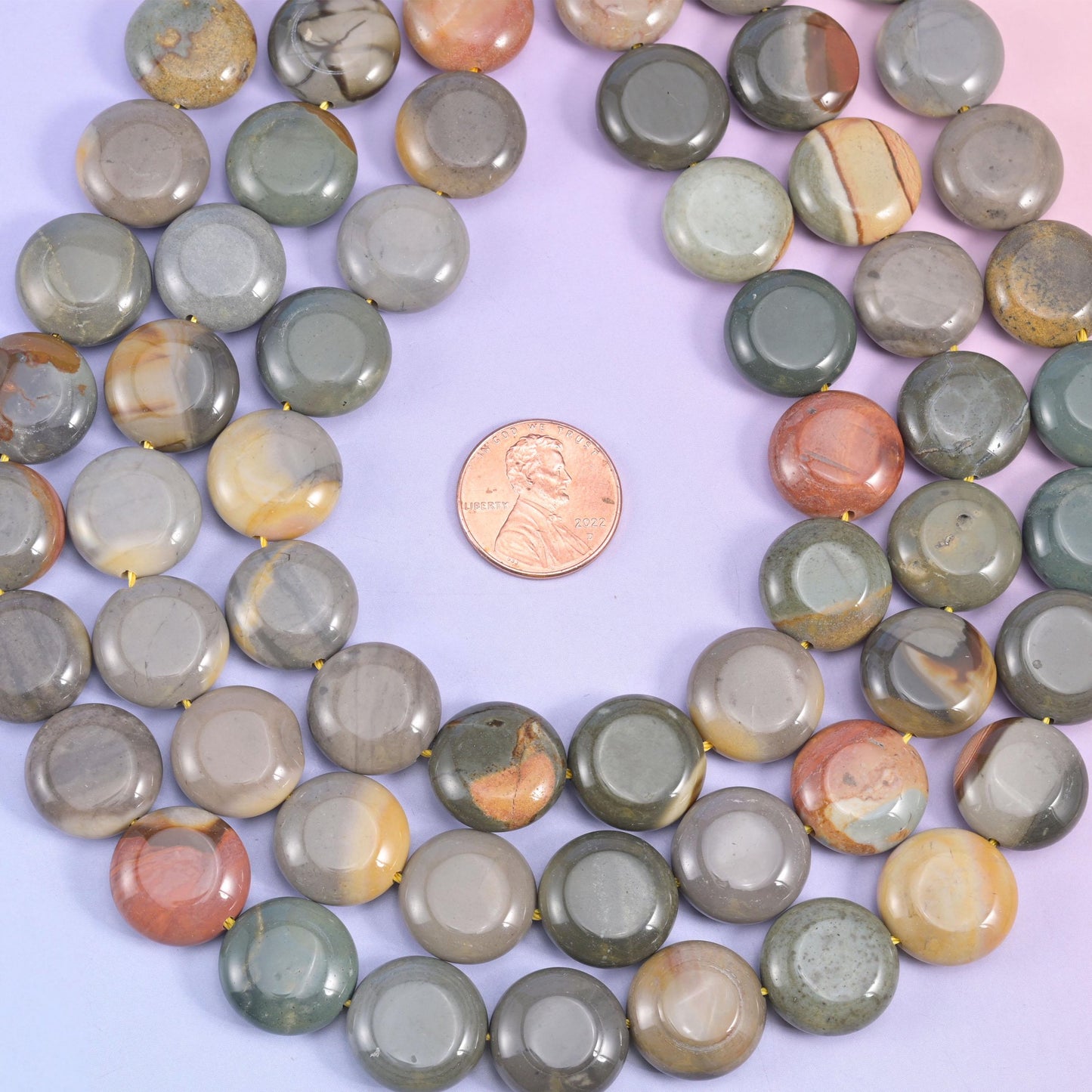 Picture jasper coins coiled around a penny, sage green and rust tones side by side
