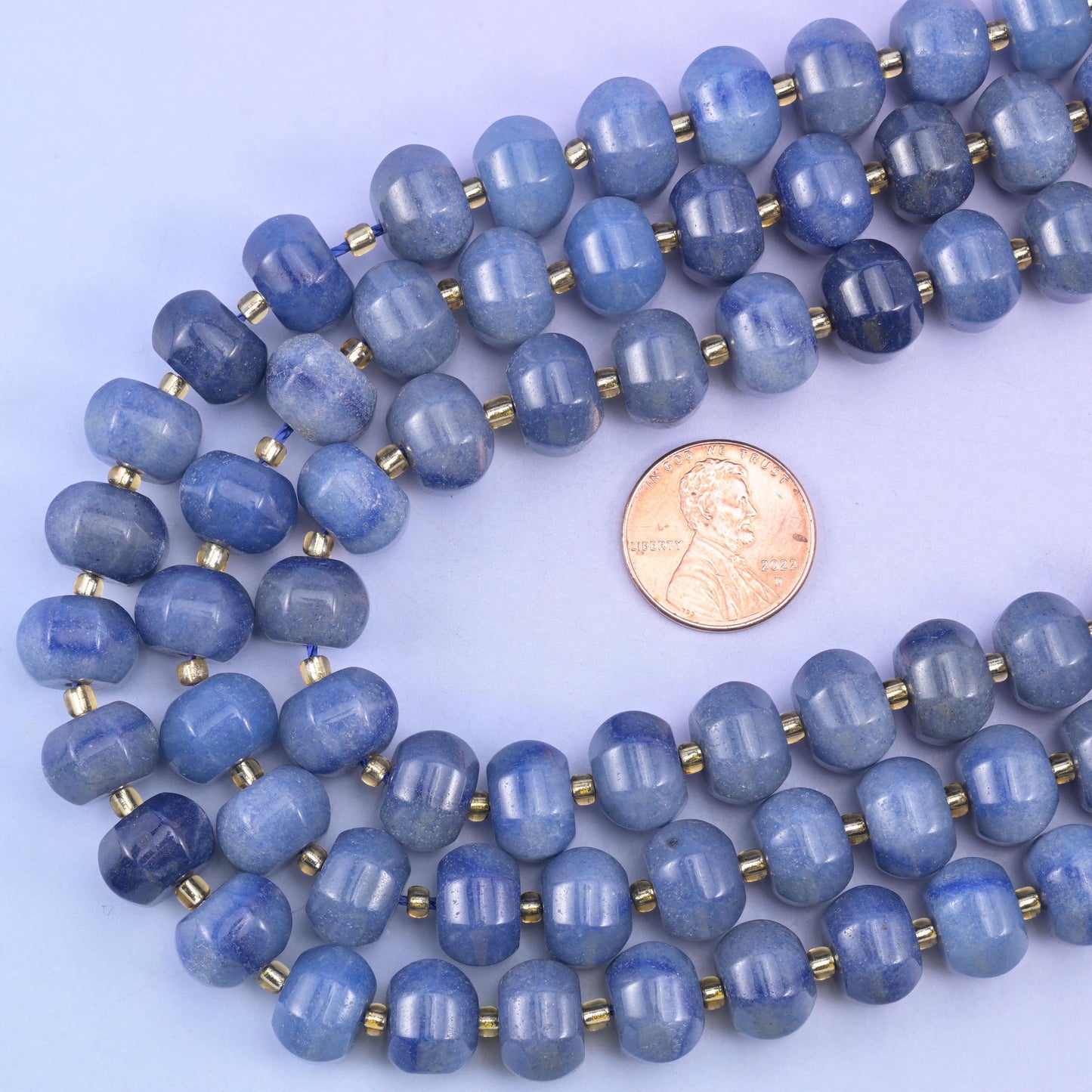 Size check: a US penny sits in the loop of the strands beside the 12x8mm Blue Aventurine beads
