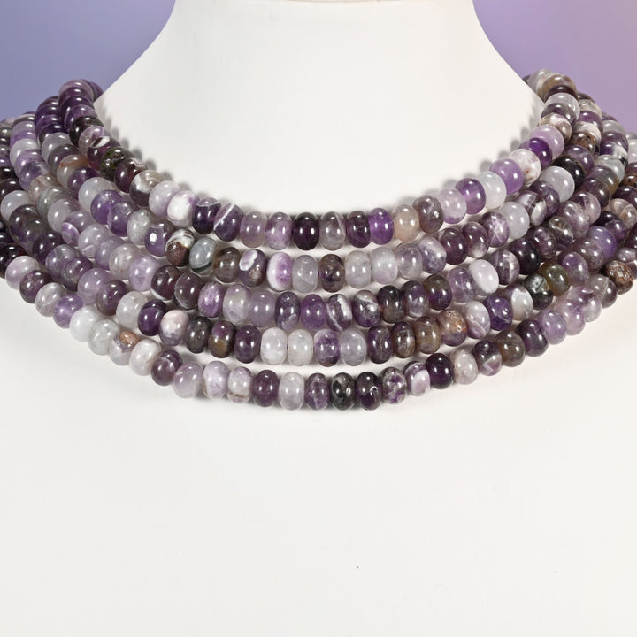 Multi-strand Amethyst necklace laid flat on a mannequin neck form against a lavender background.