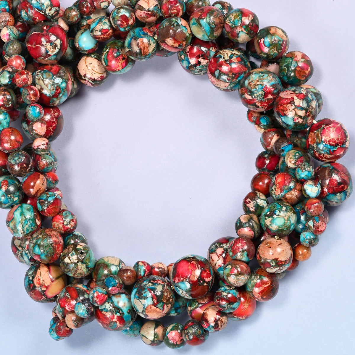 Red sea sediment jasper smooth round beads coiled into a densely packed ring with a small opening.