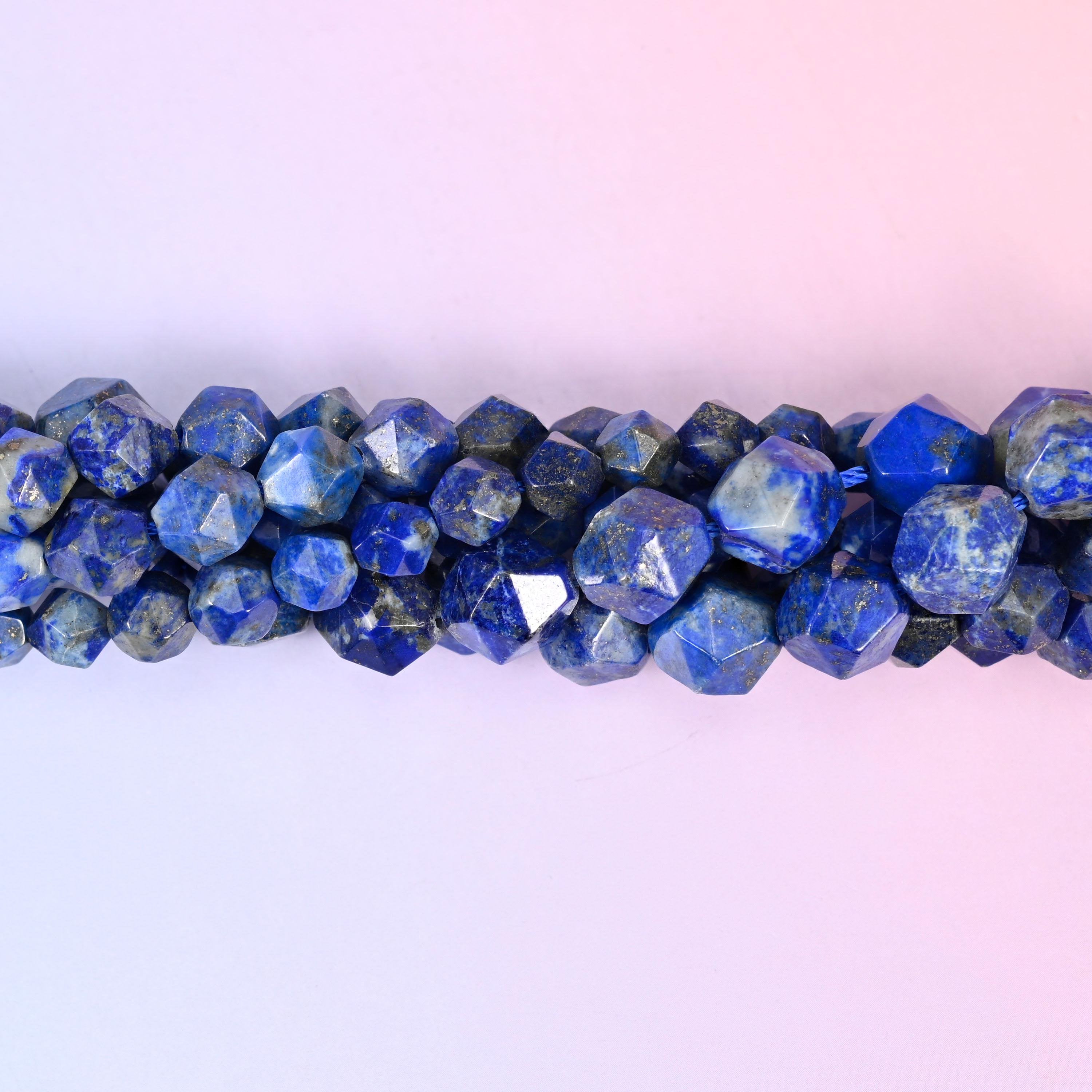 Blue Lapis Lazuli faceted beads close up in a single row, flat triangular star cut planes with small gold pyrite flecks