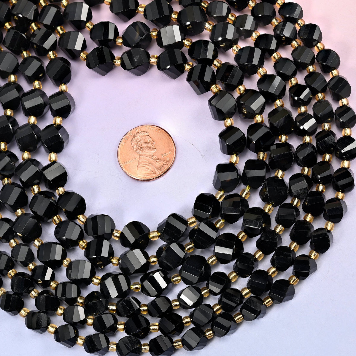 Jet black and evenly opaque, polished to a mirror finish so the spiralling facets throw sharp white highlights against the dark body. In 8mm and 10mm