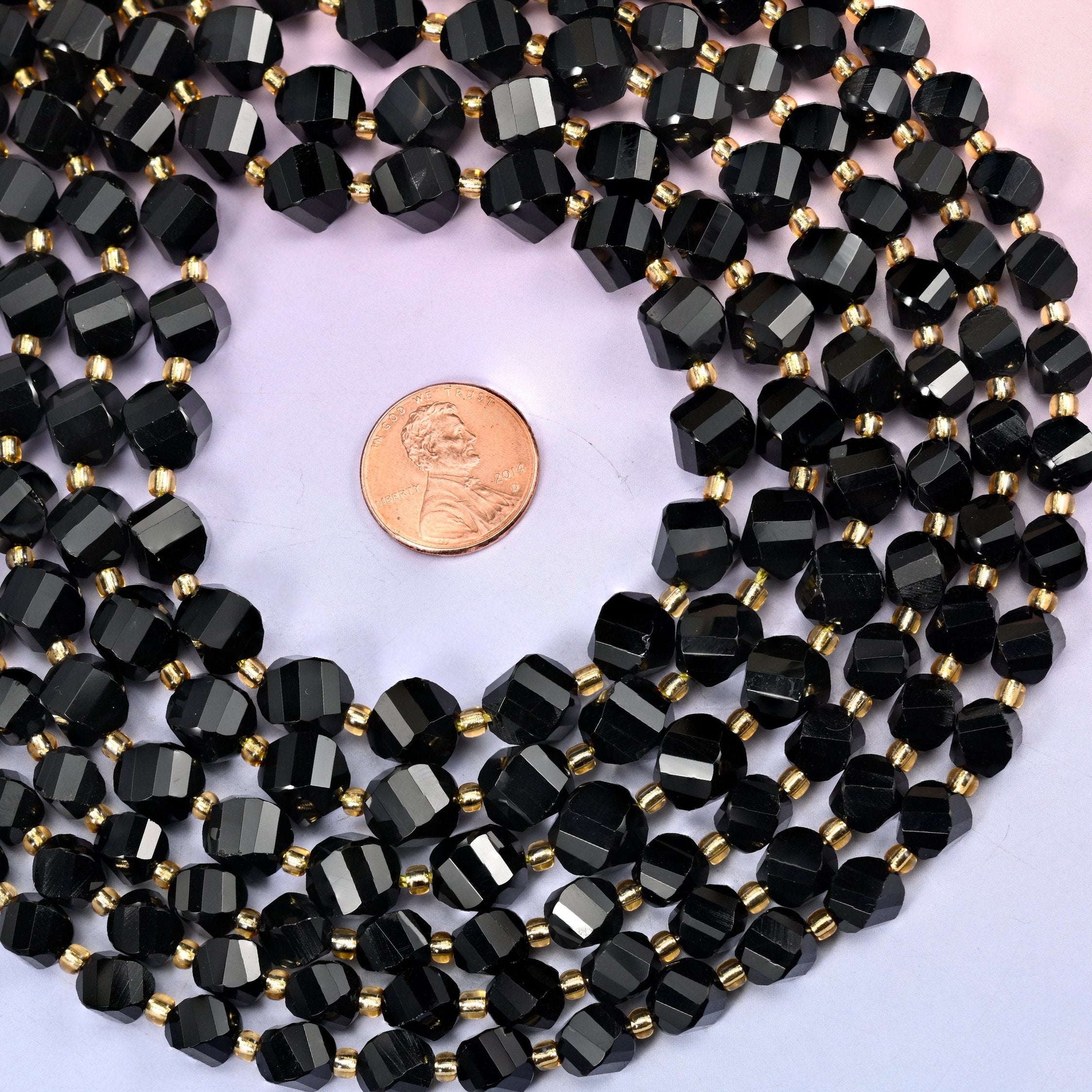 Jet black and evenly opaque, polished to a mirror finish so the spiralling facets throw sharp white highlights against the dark body. In 8mm and 10mm