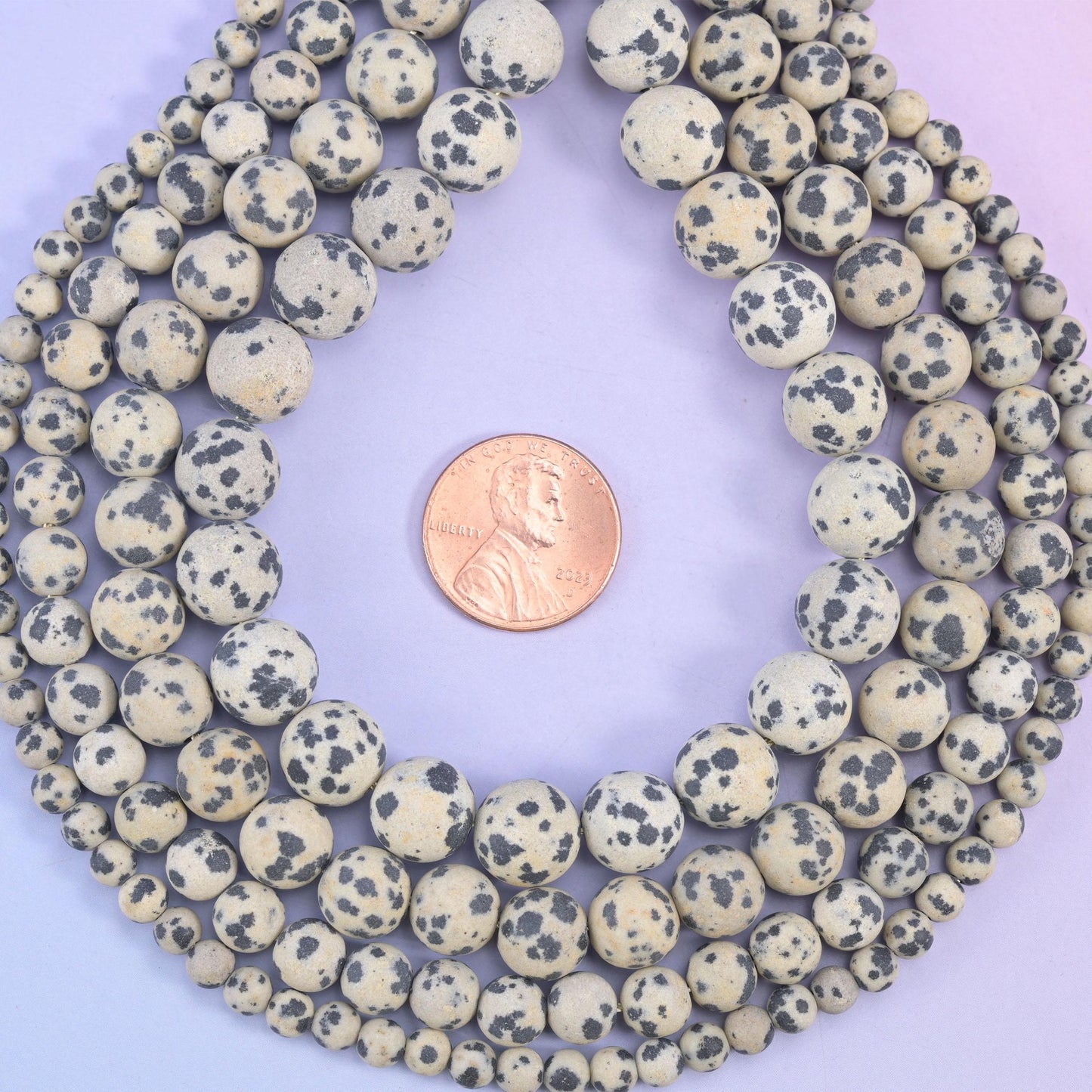 Dalmatian Jasper Matte Round Beads, a chalky frosted matte surface over oatmeal cream stone scattered with charcoal grey and black spots