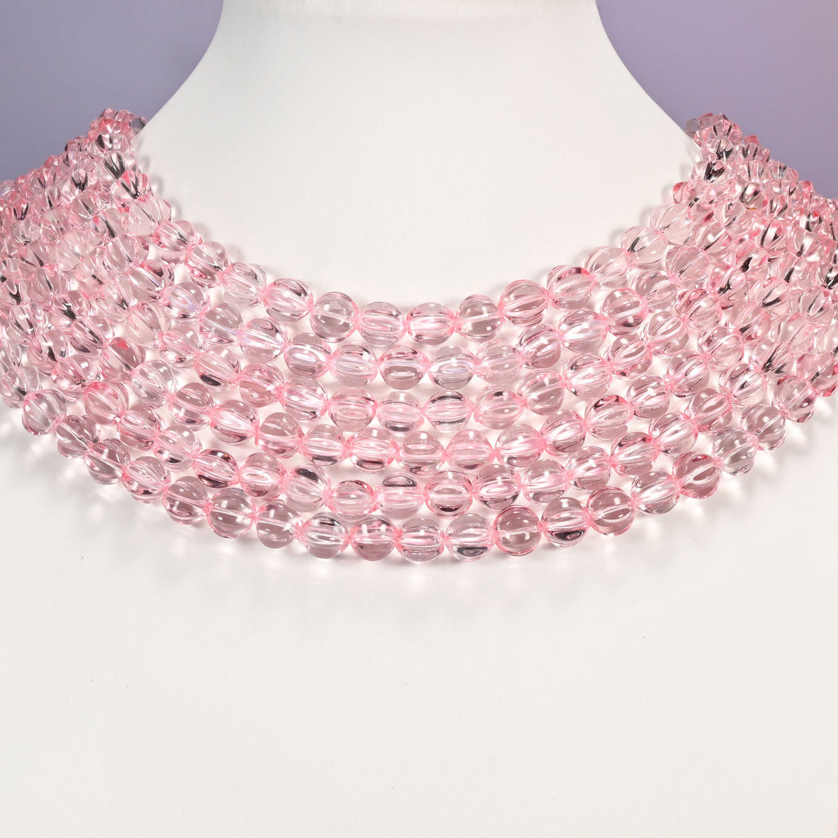 Clear pink pumpkin glass beads shown as layered strands on a white neck display form.