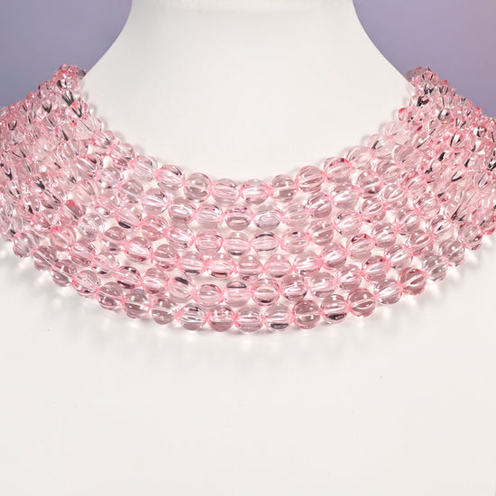 Clear pink pumpkin glass beads shown as layered strands on a white neck display form.