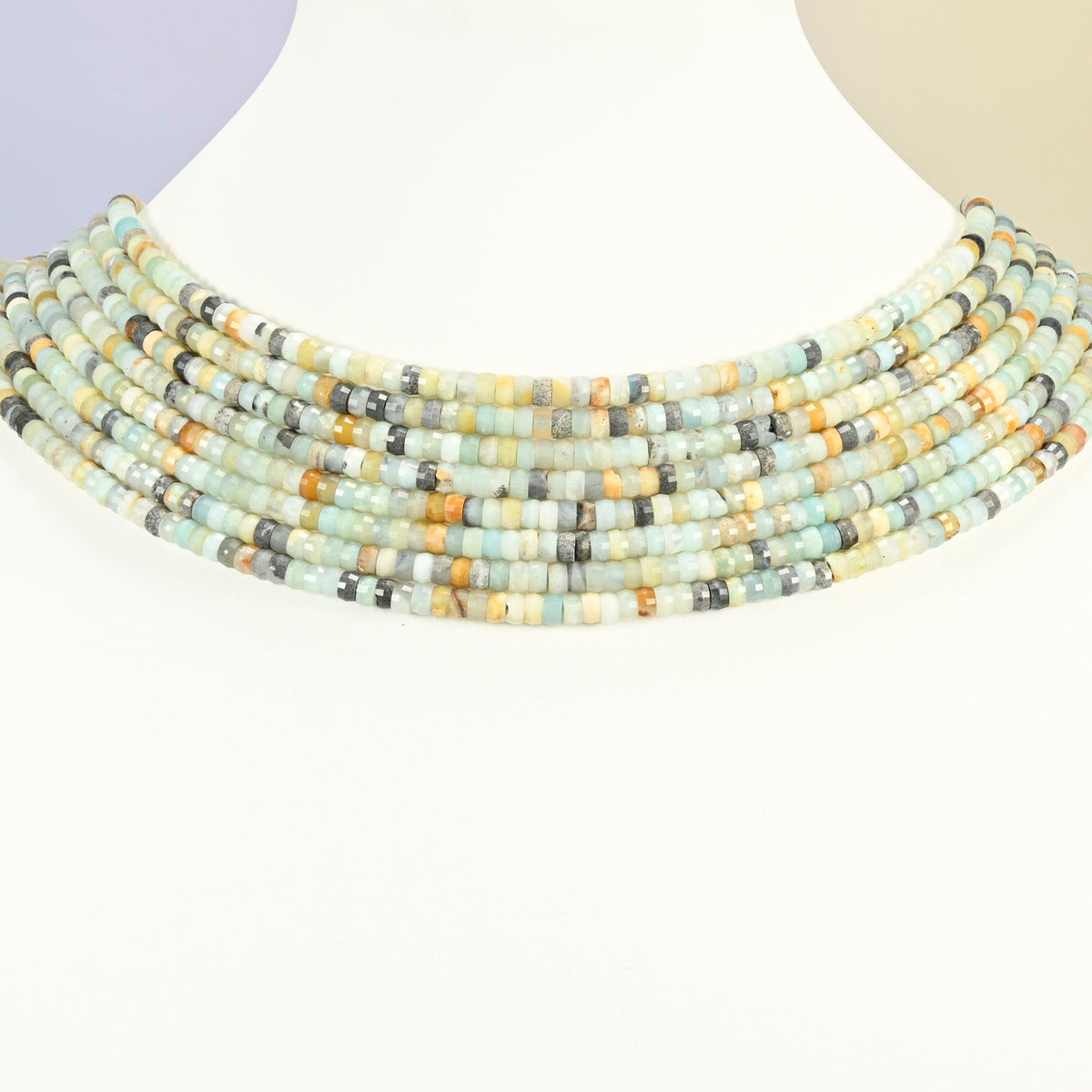 Multi-color amazonite faceted heishi disc strands arranged as a layered collar on a white display bust, blue-green and cream beads across the neck
