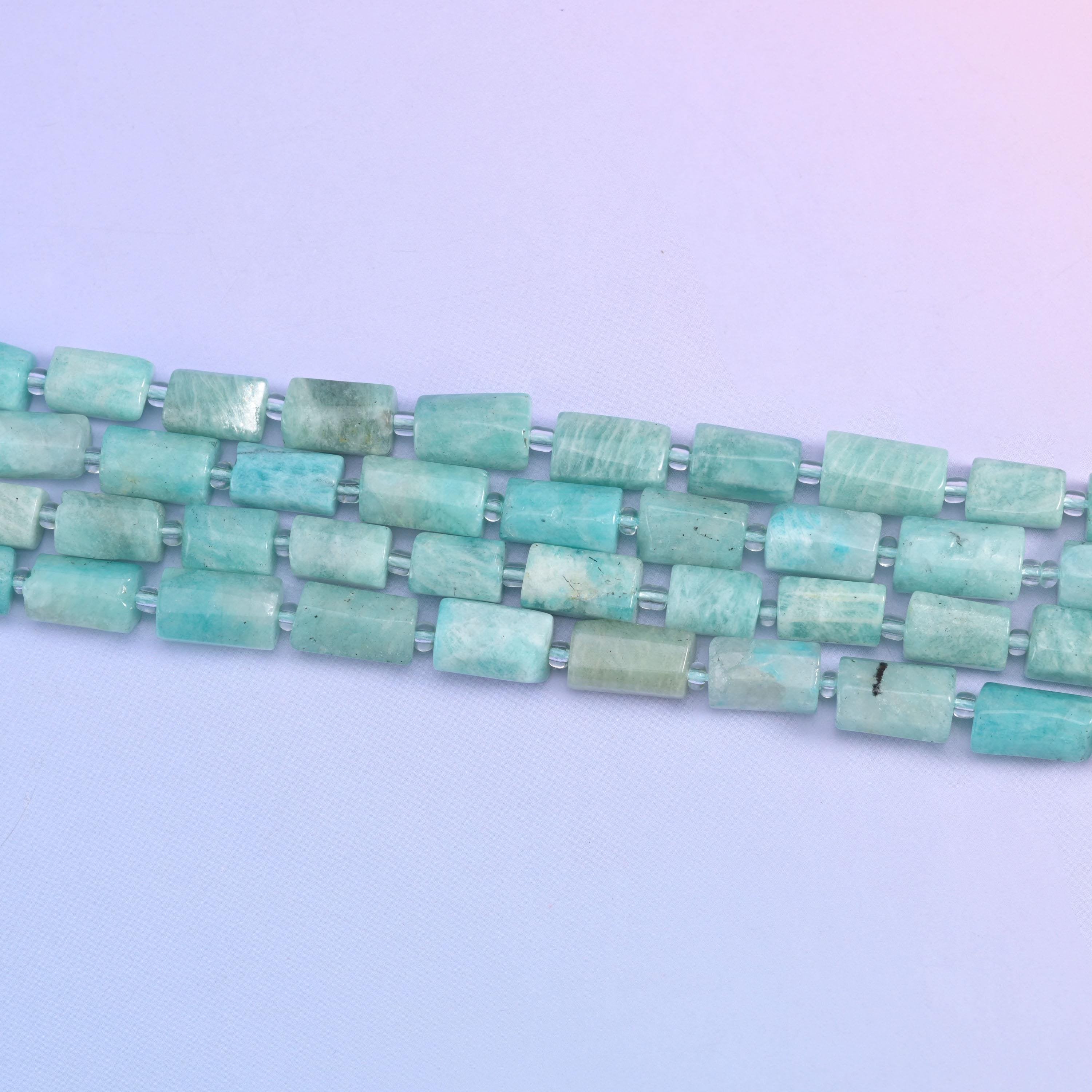 Straight rows of seafoam amazonite tube beads laid flat, showing even 12x8mm sizing and clear spacers