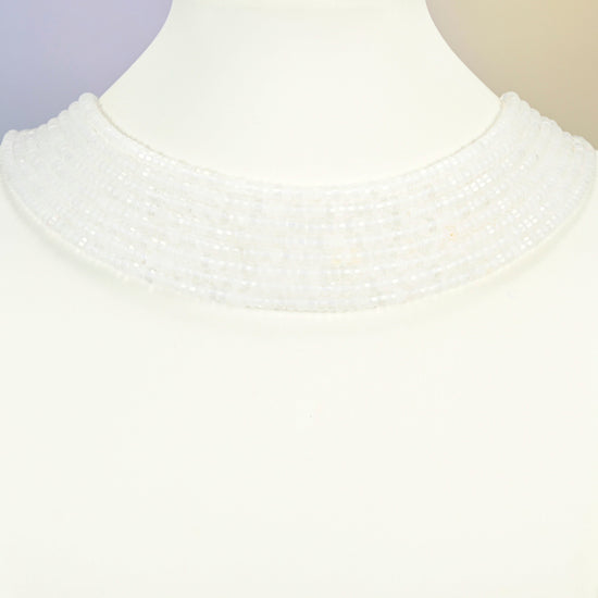 Clear quartz faceted heishi disc strands arranged as a layered collar on a white display bust, clear beads across the neck