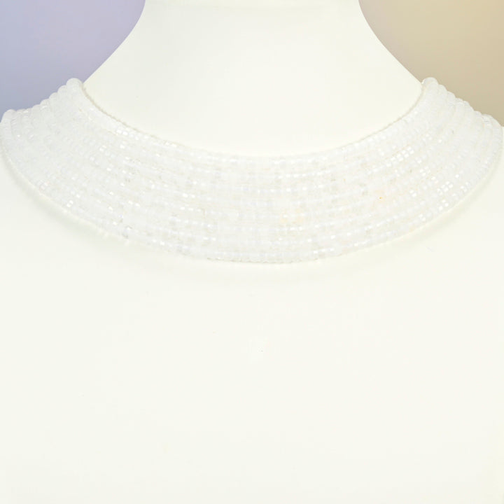 Clear quartz faceted heishi disc strands arranged as a layered collar on a white display bust, clear beads across the neck