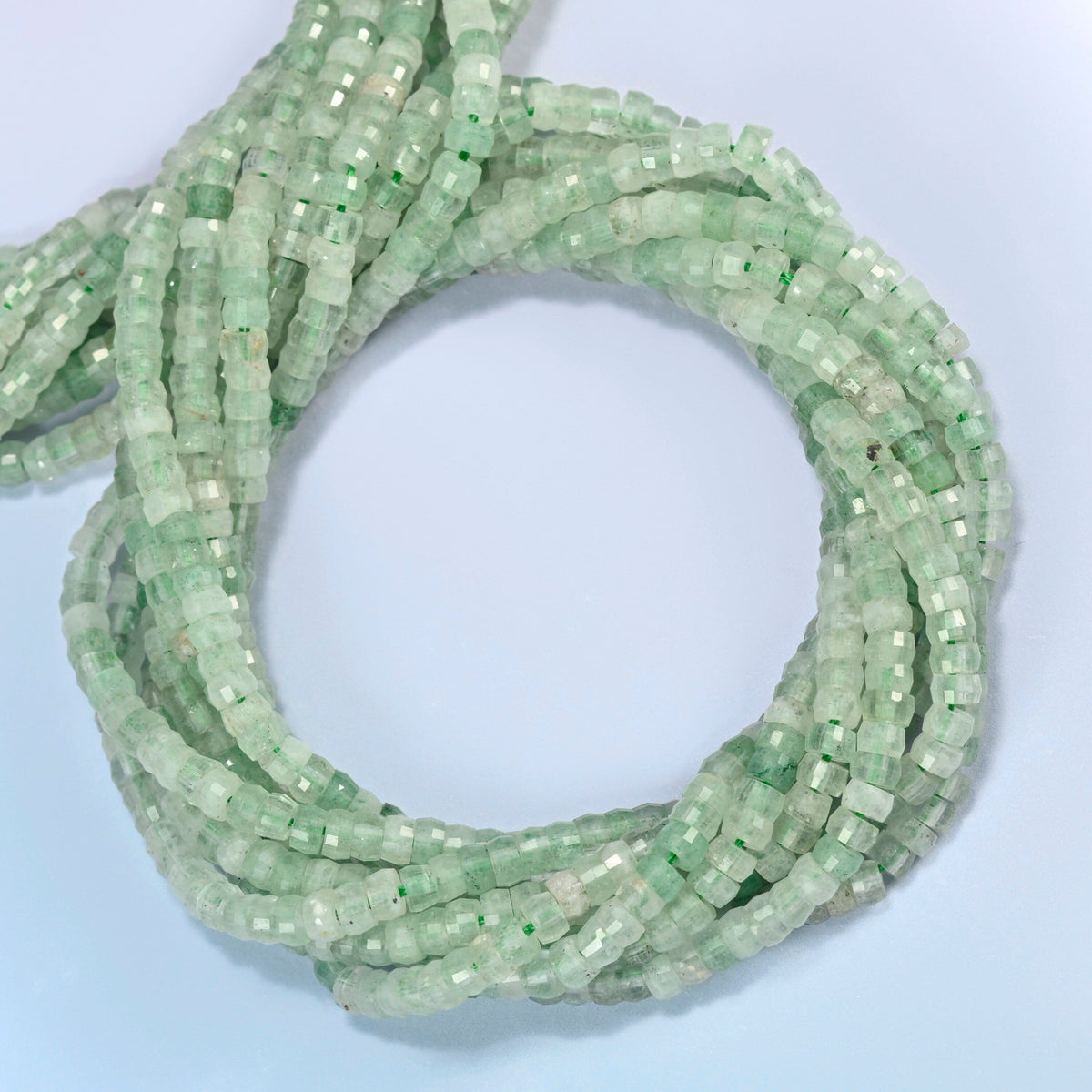 Green strawberry quartz faceted heishi disc beads coiled into overlapping loops, whole strands of light green quartz