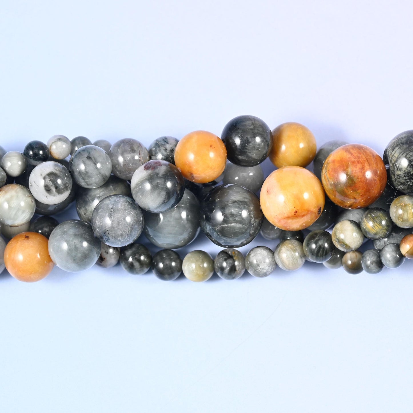 Silver-grey with black streaking and a shifting cat's-eye sheen, Eagle Eye Jasper Round Beads come strung with warm ochre and apricot beads