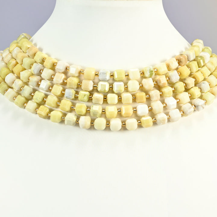 Butter jade faceted cube beads on a white neck display, five strands stacked around the bust.