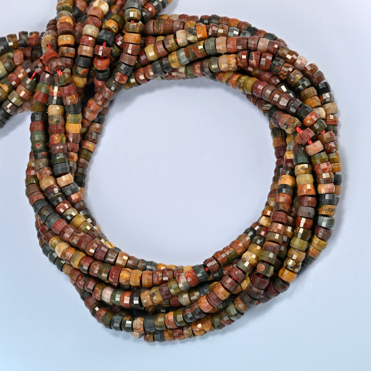 Red howlite faceted heishi disc beads coiled into overlapping loops, whole strands of earthy multicolor stone