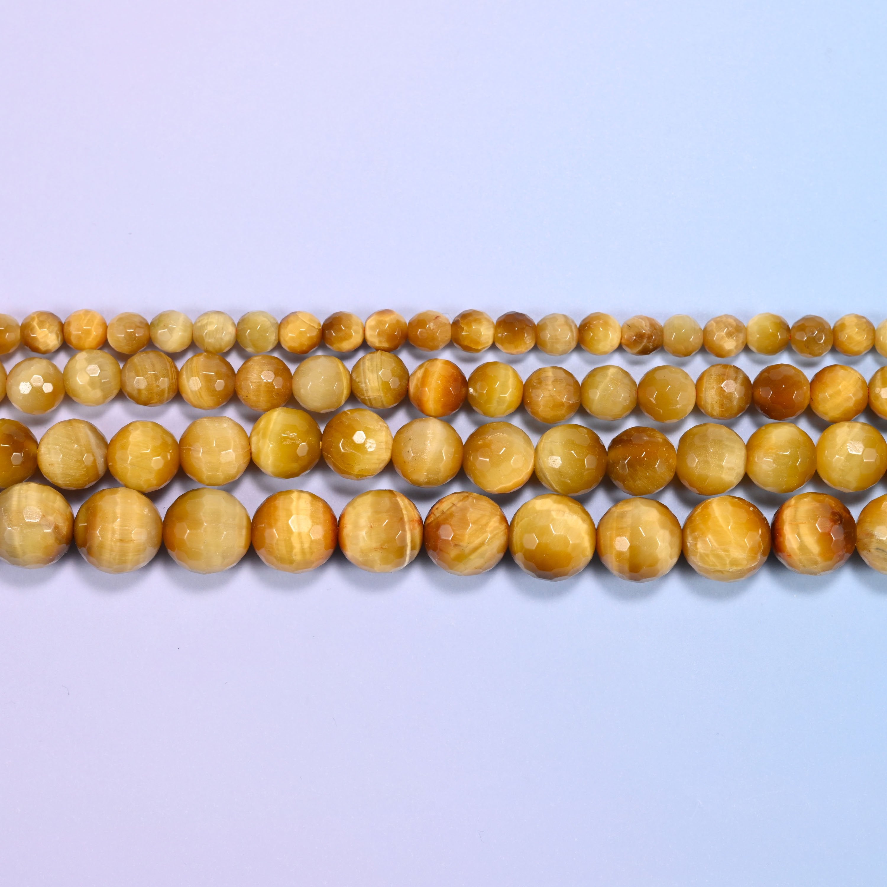 Full 15-inch strand of golden brown gold tiger eye round beads laid out for jewelry making.