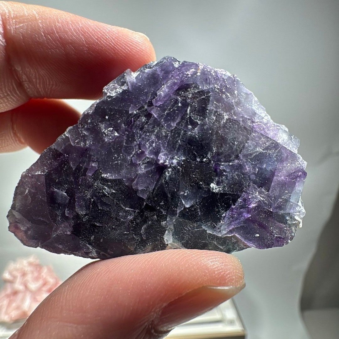 The fluorite slab cupped in a palm, giving a sense of its small hand-held size
