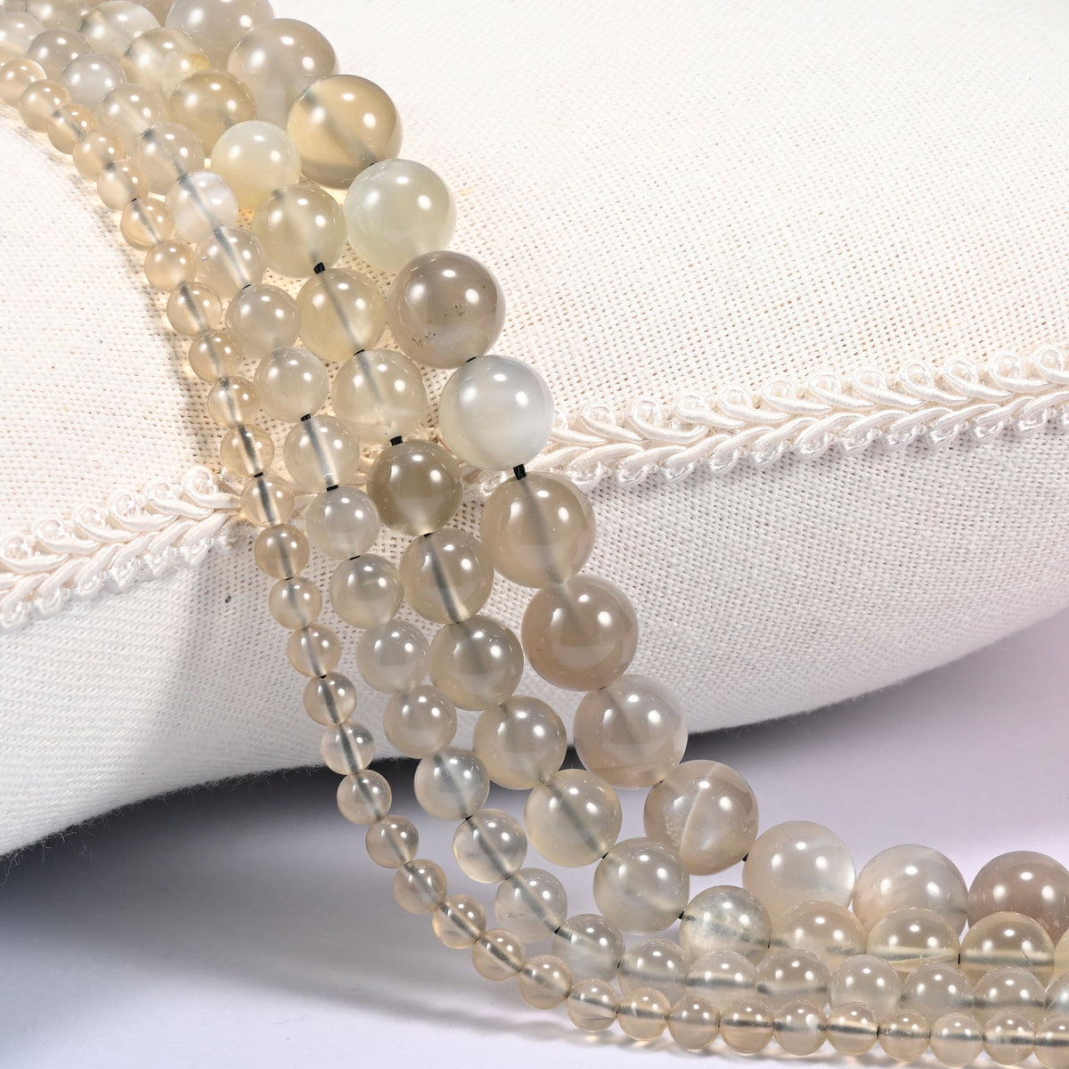 AAA Gray Labradorite smooth round beads draped in a soft curve, translucent white through light gray
