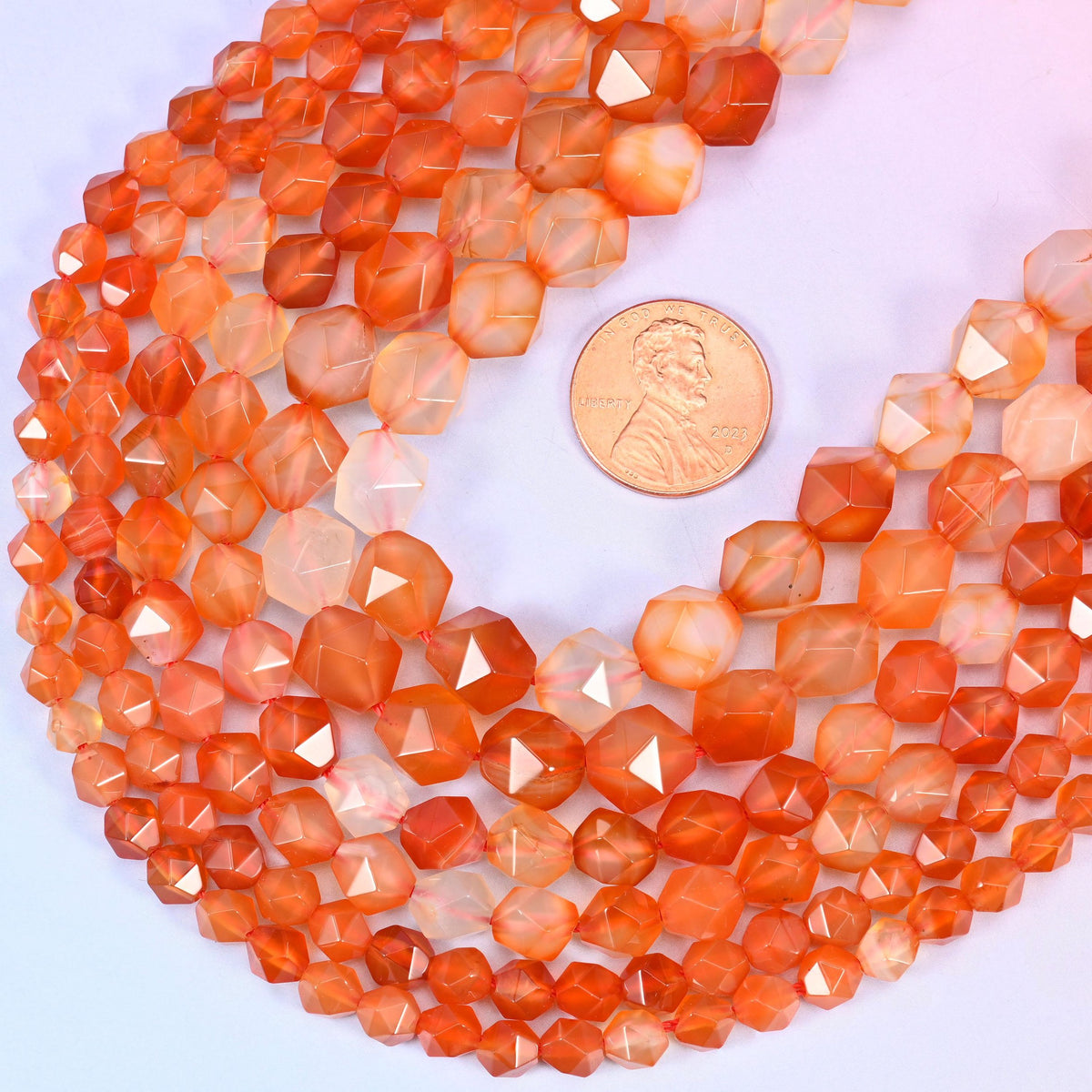 Orange Agate star cut beads with a US penny alongside for size reference, available in 6mm, 8mm and 10mm