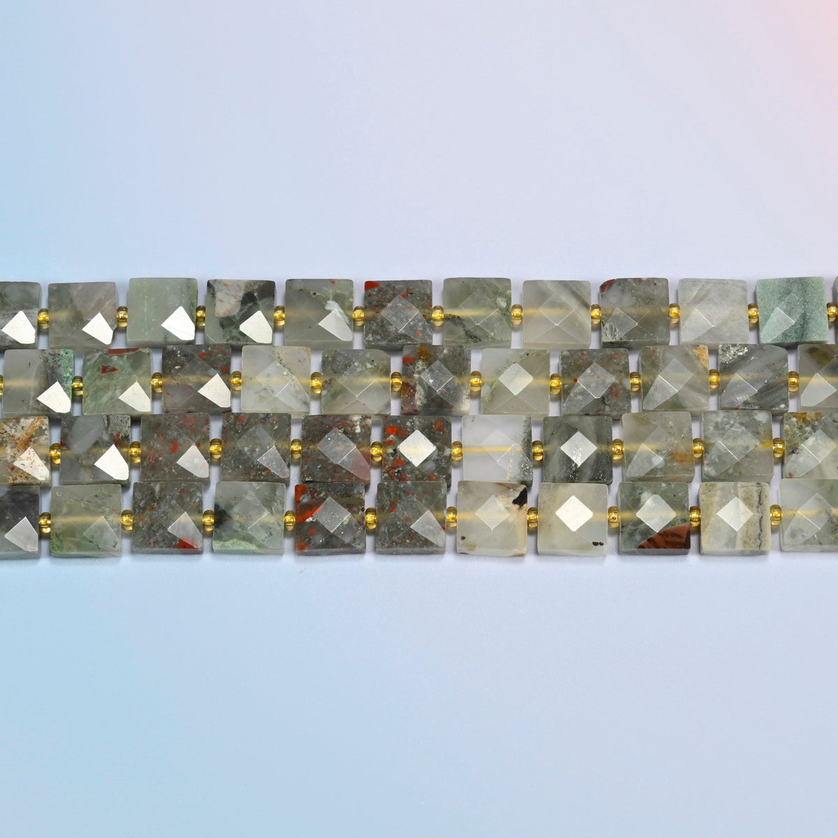 Several strands of natural African bloodstone faceted flat square beads laid in straight rows