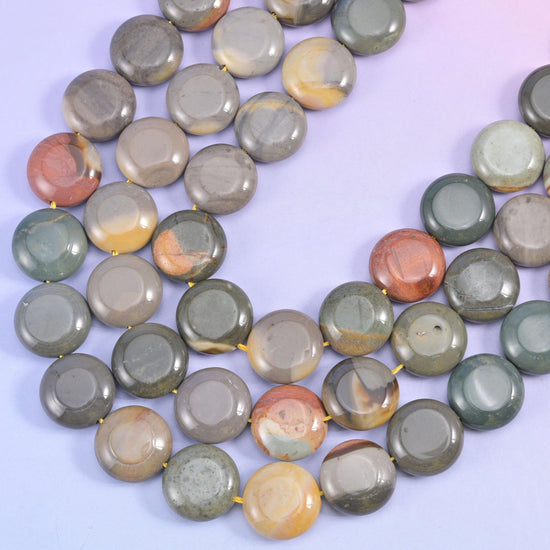 Two picture jasper strands crossing on a soft blue backdrop, a terracotta bead among the grey