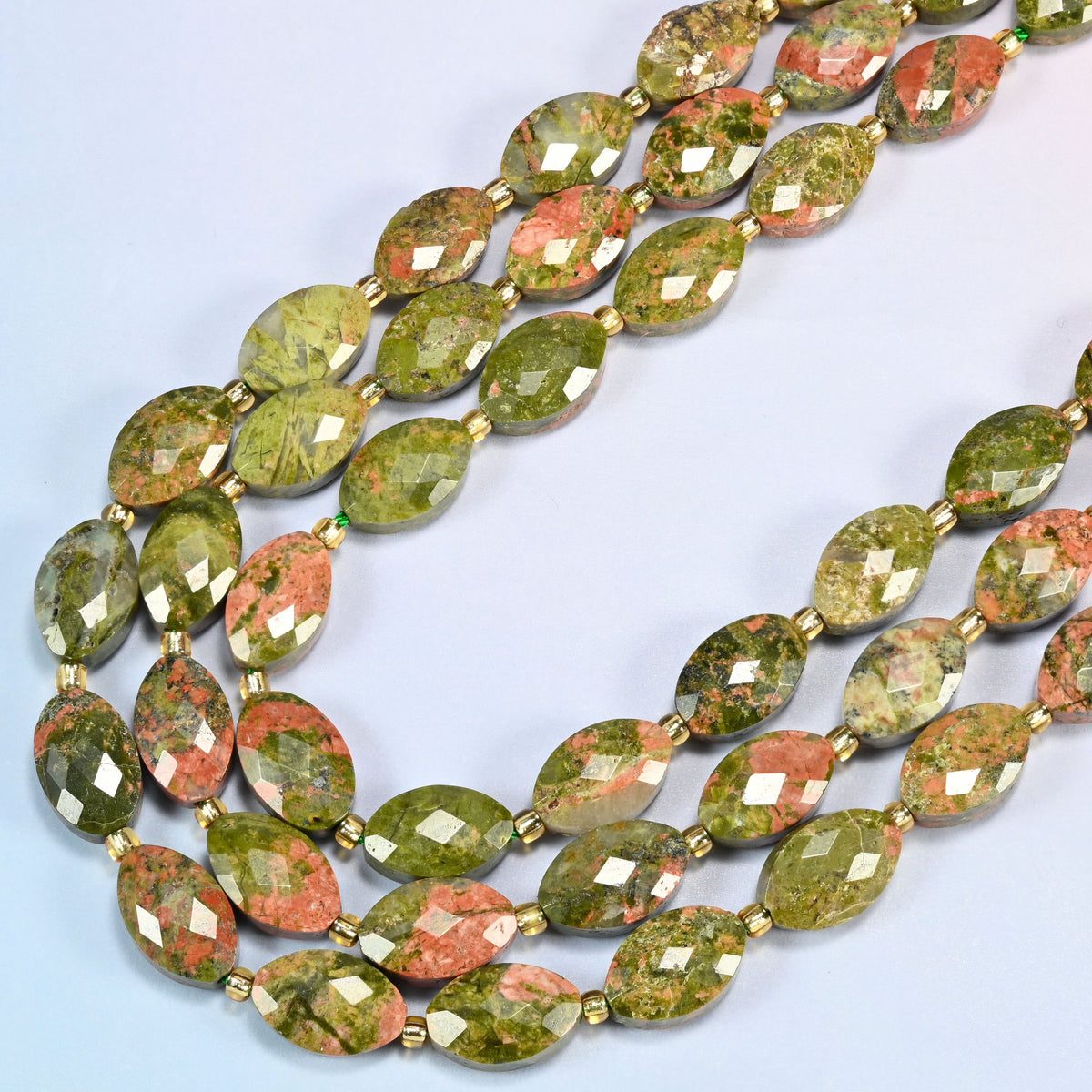 Unakite faceted flat oval beads in several strands curved into a wide U, green and pink stone