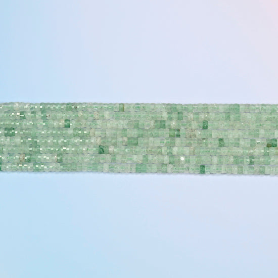 Several strands of green strawberry quartz faceted heishi disc beads laid in straight rows
