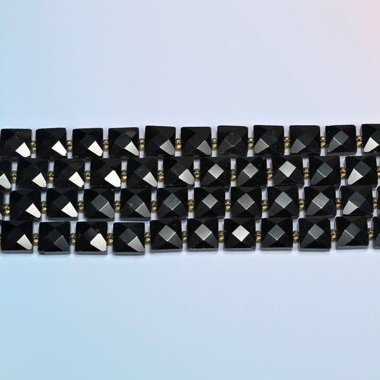 Several strands of natural black onyx faceted flat square beads laid in straight rows