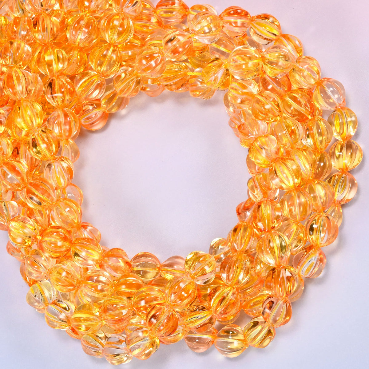Yellow gold pumpkin glass beads coiled with the open center to one side, showing the fluted grooves end on.