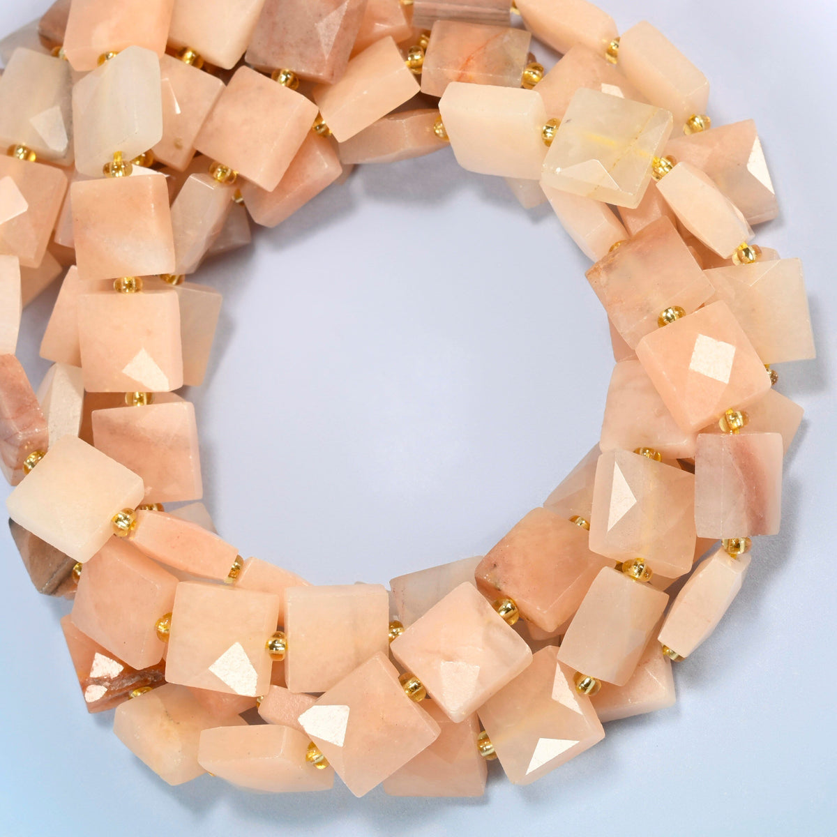 Natural pink aventurine faceted flat square beads coiled into overlapping loops, whole strands of soft peach pink stone