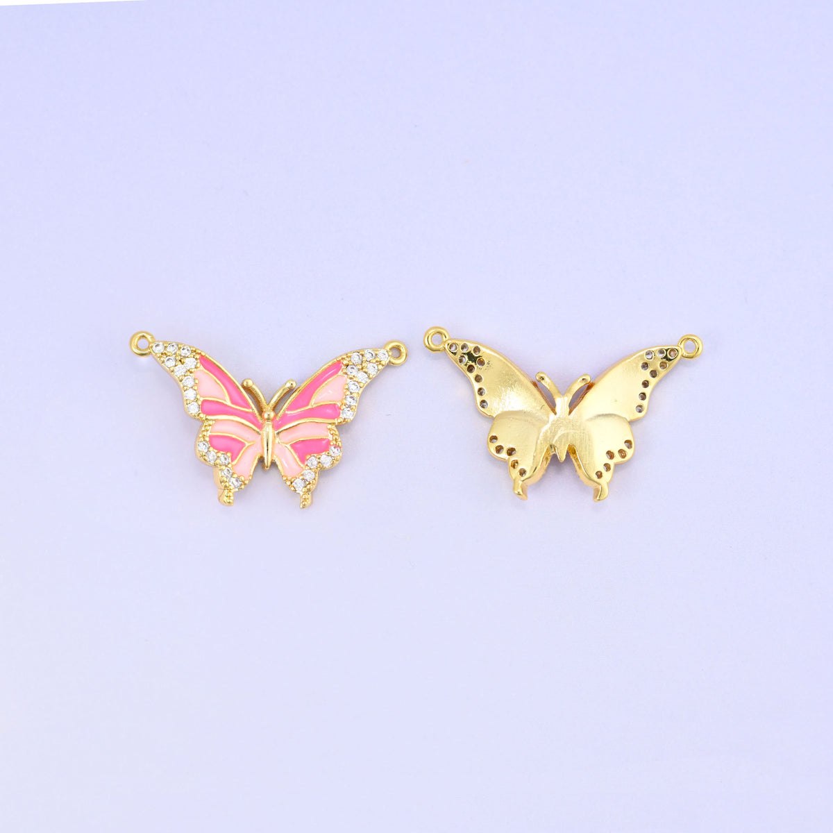 Pink enamel butterfly double connector pendant paired with the reverse of a second charm, showing the smooth gold back and its speckled wing detail.
