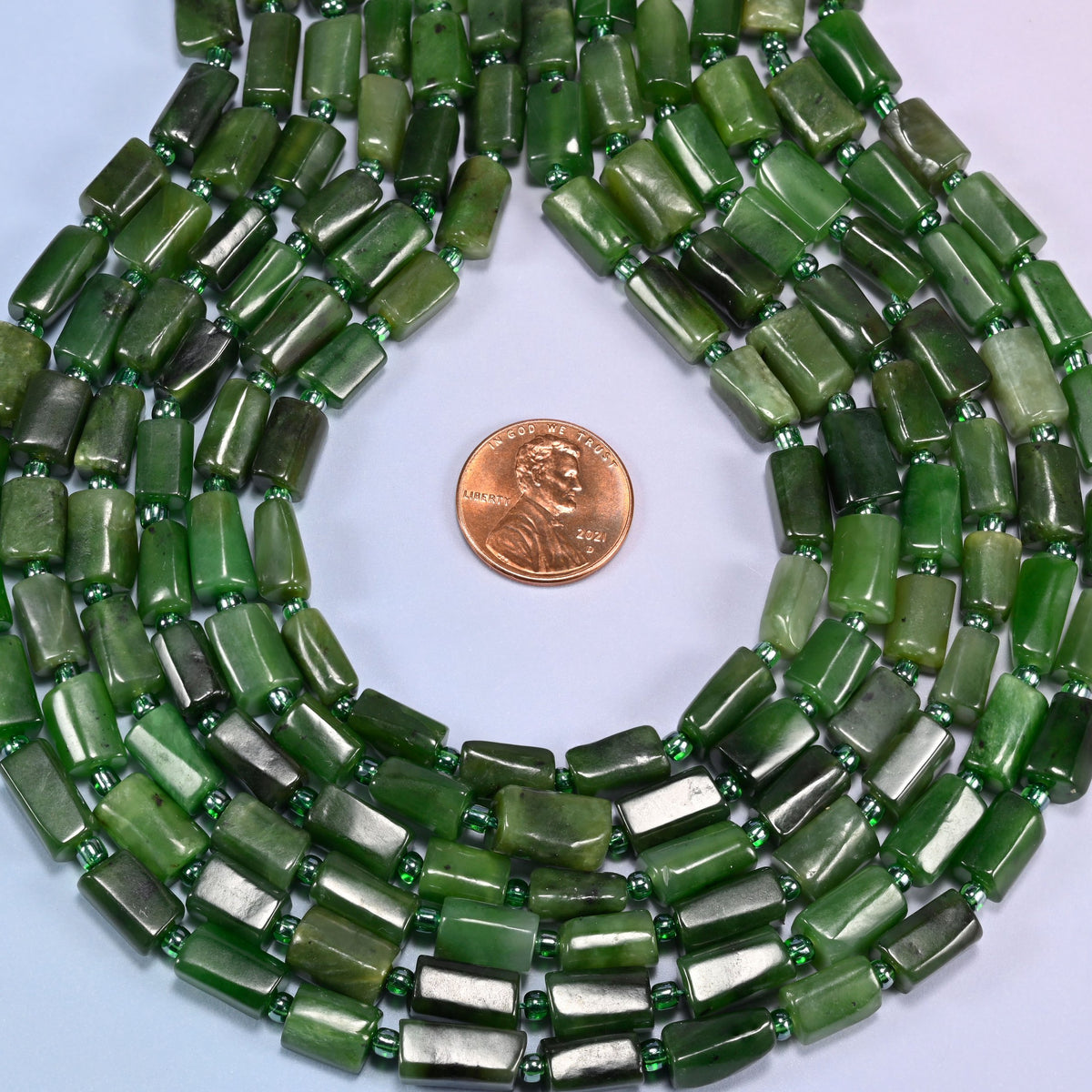 Canadian Green Jade faceted tube beads in a teardrop coil, bead length running 8mm to 12mm along the strand at a steady 7mm width