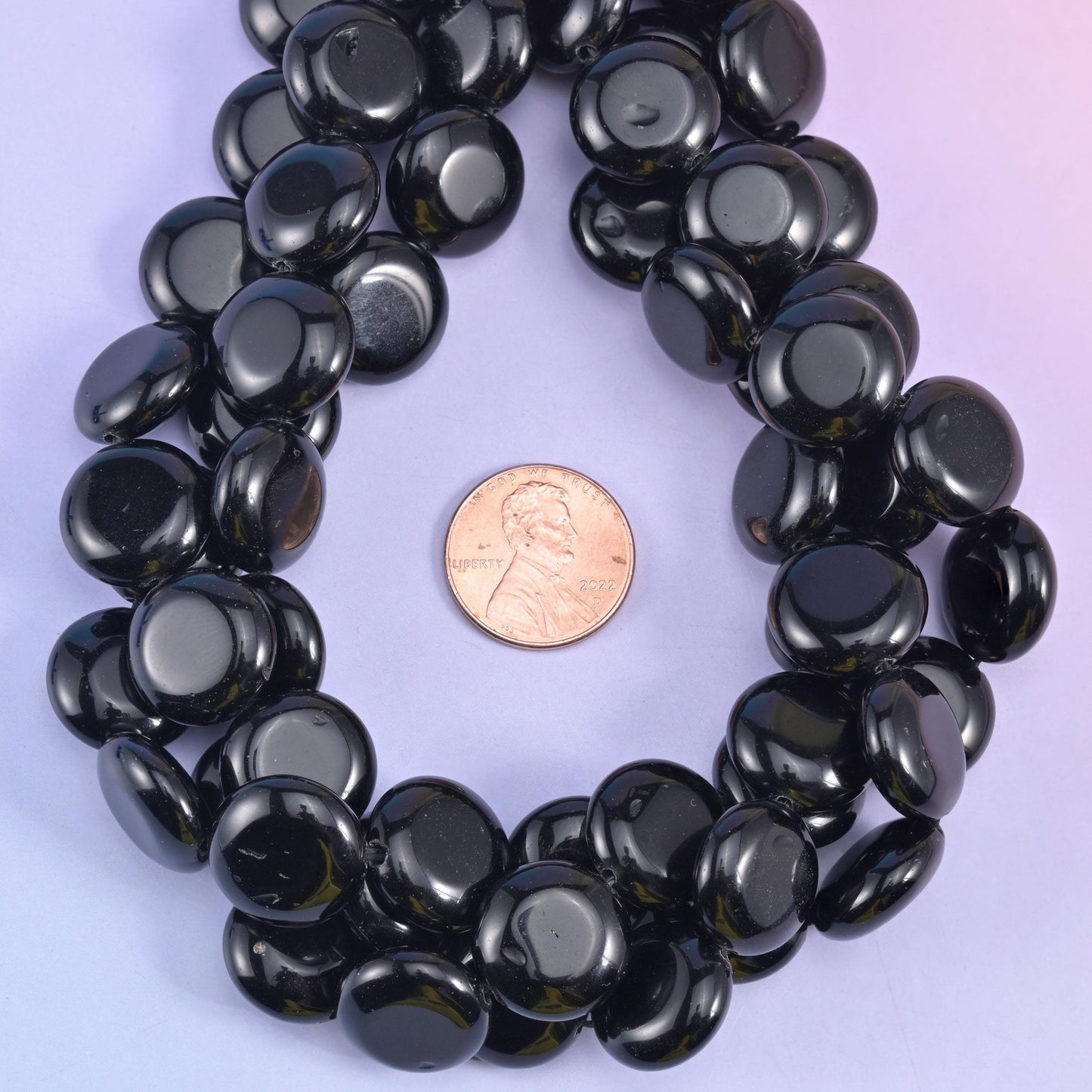 Coin beads circling a penny on lilac, discs evenly matched in diameter around the loop