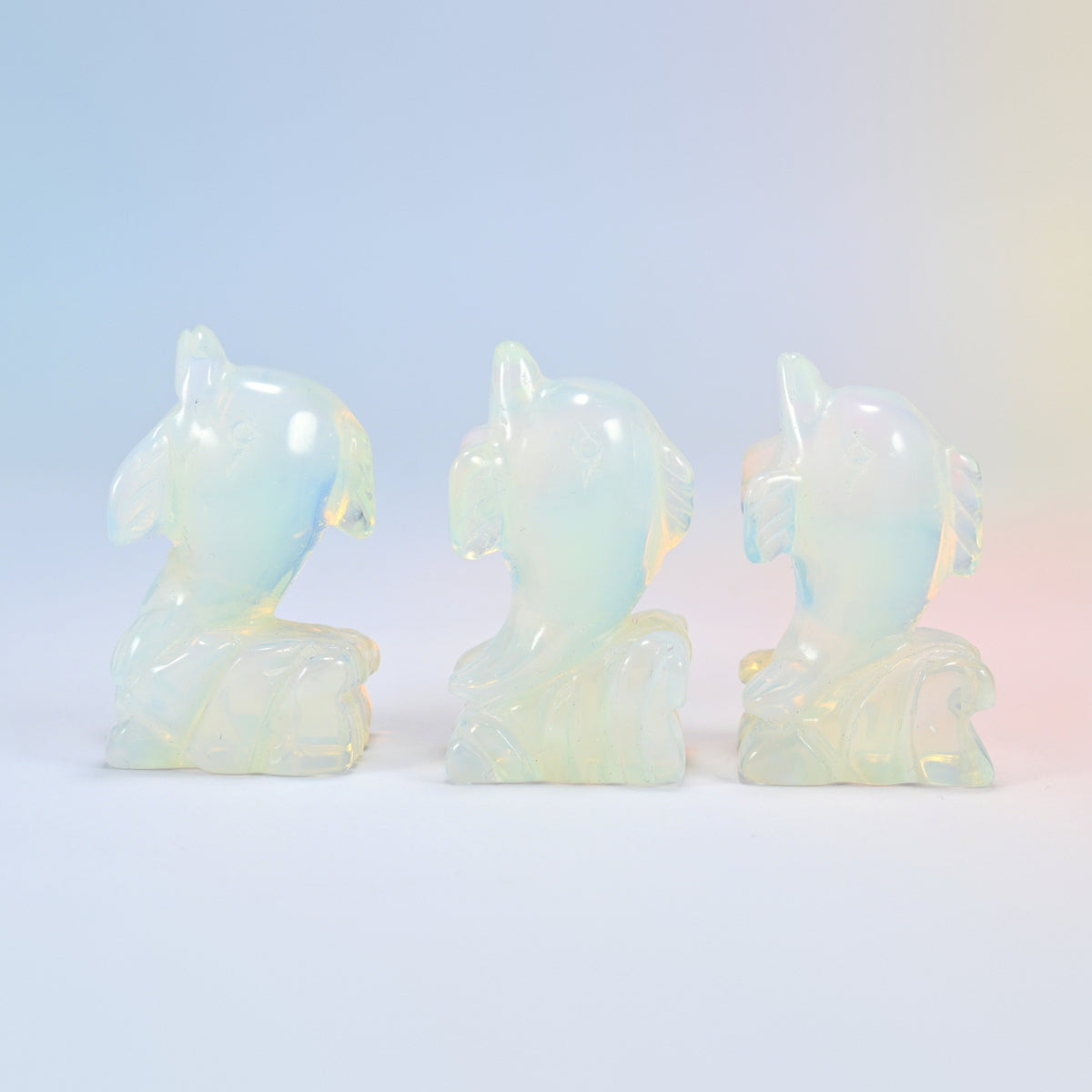 Three 2 inch opalite dolphin carvings, each leaping from a carved wave, glowing man-made glass