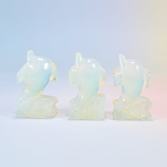 Three 2 inch opalite dolphin carvings, each leaping from a carved wave, glowing man-made glass