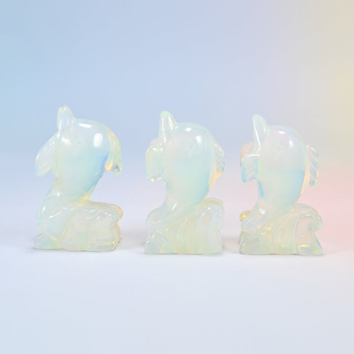 Three 2 inch opalite dolphin carvings, each leaping from a carved wave, glowing man-made glass