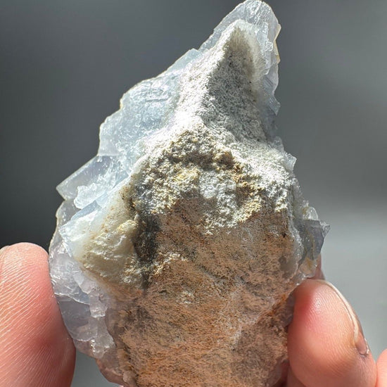 Reverse of the specimen showing the rough tan host rock the blue fluorite crystals grew on