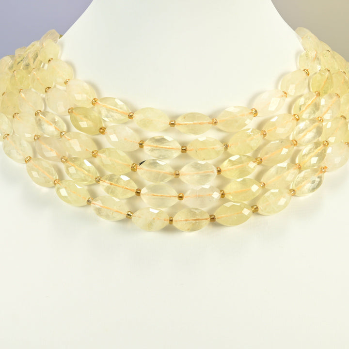 Citrine faceted flat oval strands arranged as a layered collar on a white display bust, light yellow beads across the neck