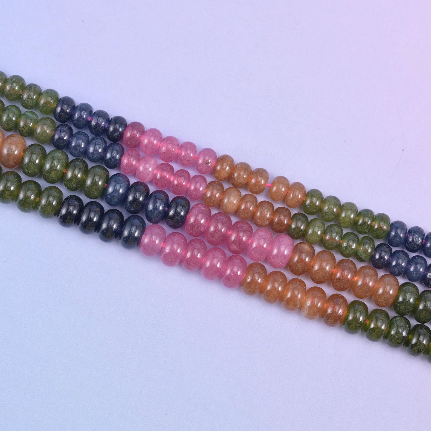 Tourmaline color dyed jade beads running through olive green, deep navy, rose pink and warm peach