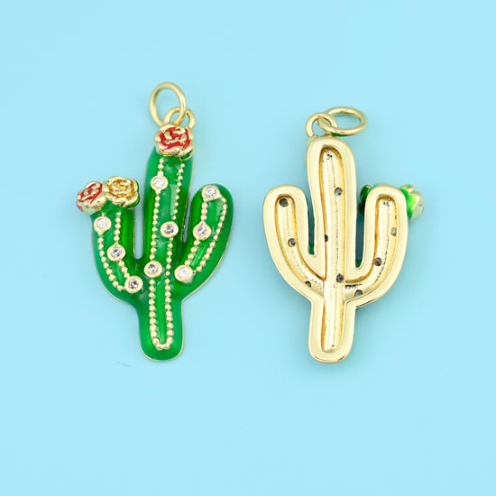 A three-armed saguaro in glossy enamel with a tiny coral red bloom at the crown, ribbed down the body with dotted lines of…
