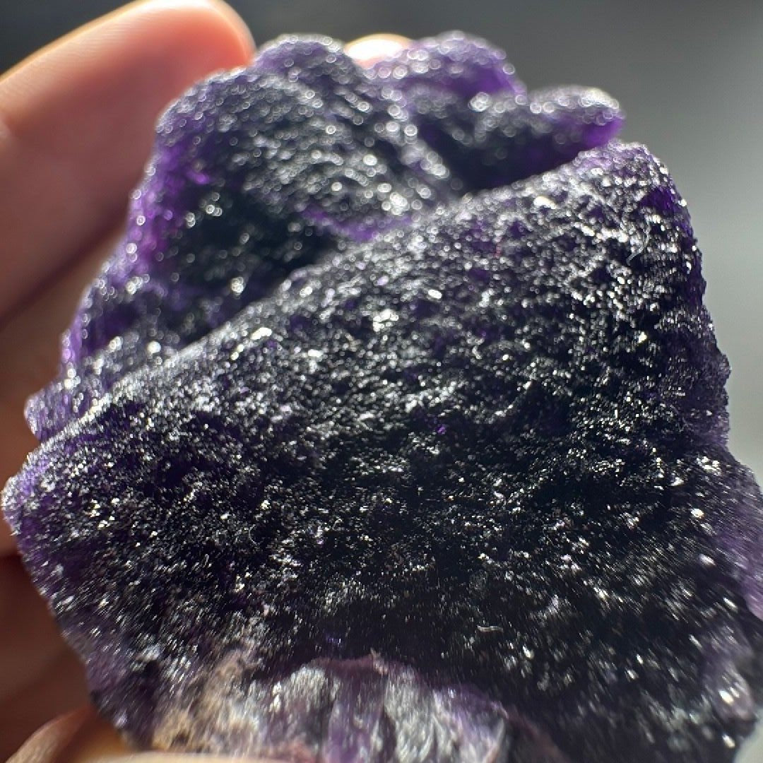 Close-up of sparkling druzy quartz coating over dark purple fluorite.